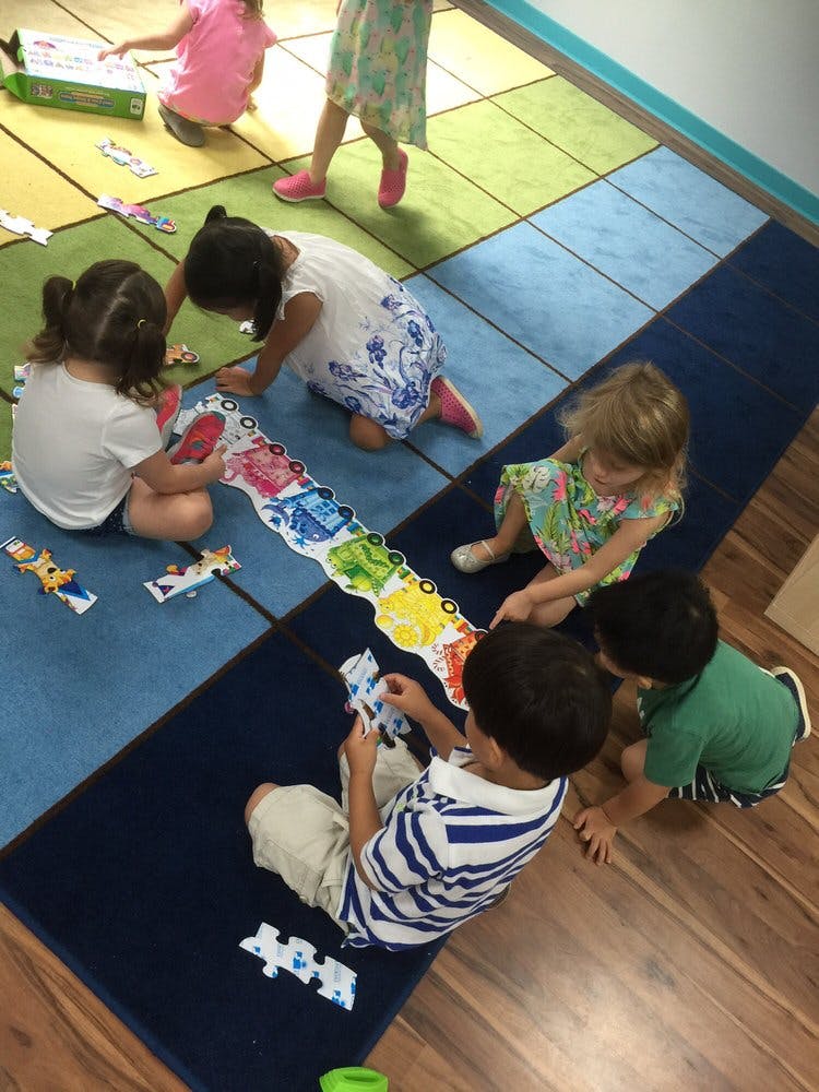 Children playing with puzzles on a colorful rug