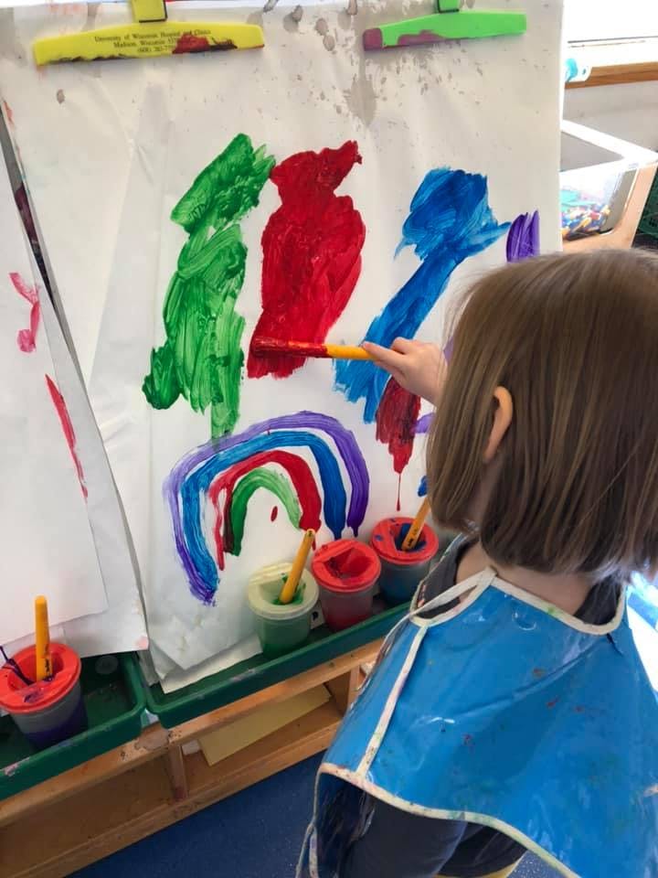 Child painting on an easel in a classroom