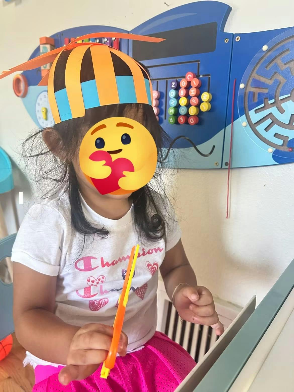 Child wearing a paper crown at a table with toys