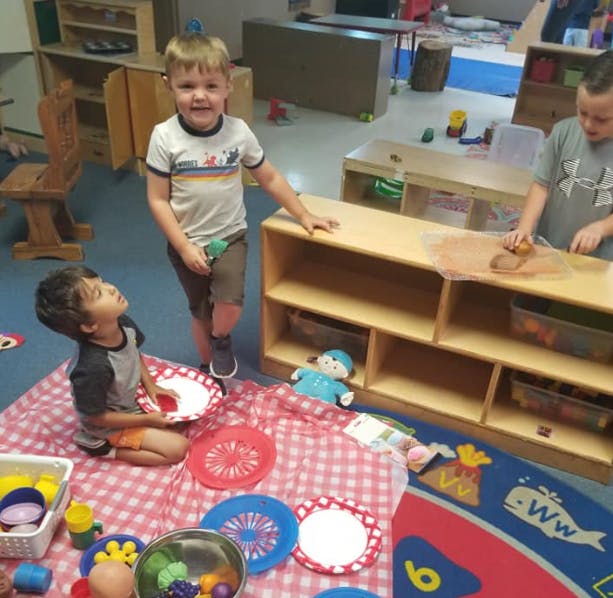 Three children playing in a classroom
