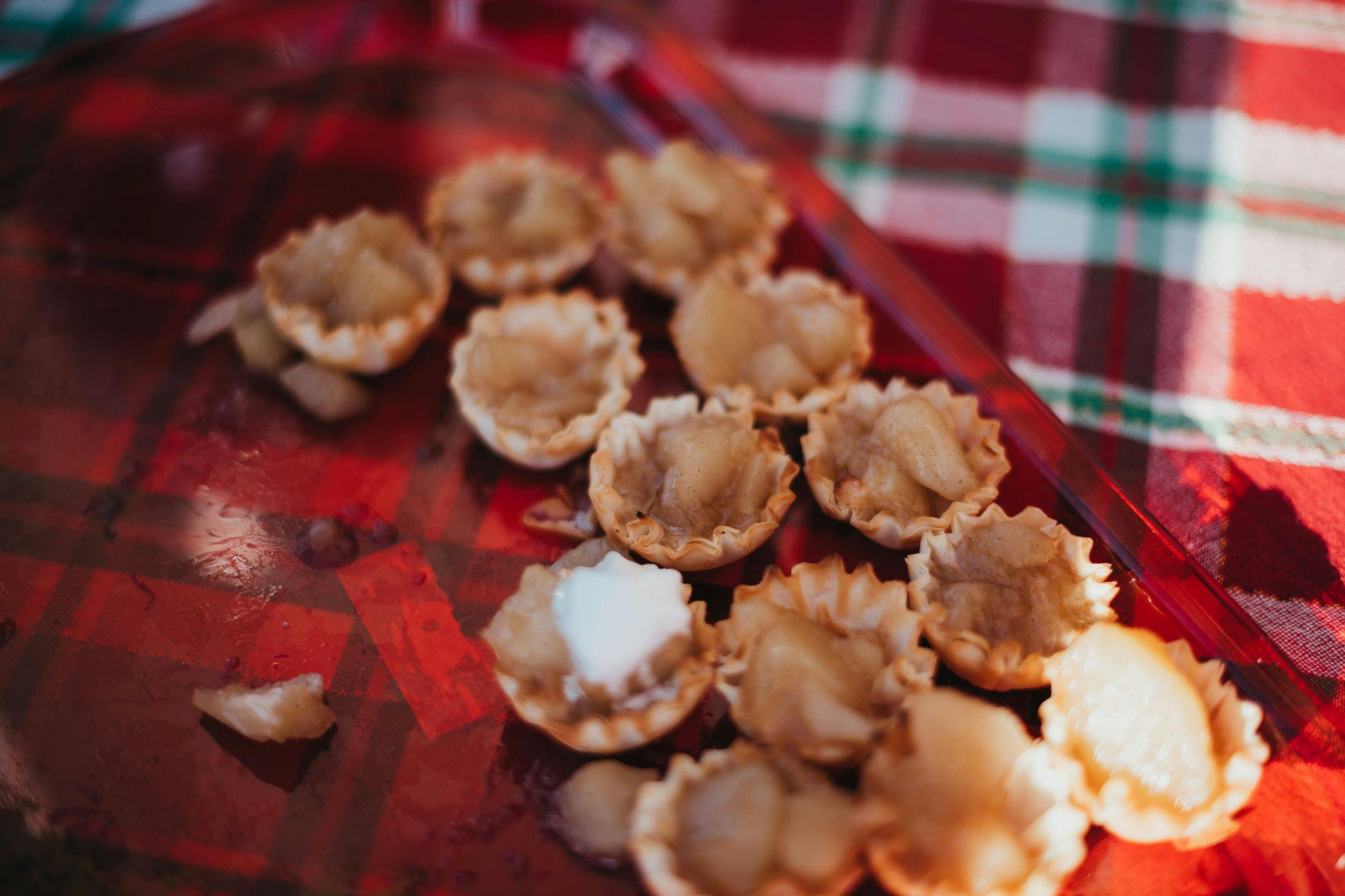 Small tarts with fruit filling on a red surface