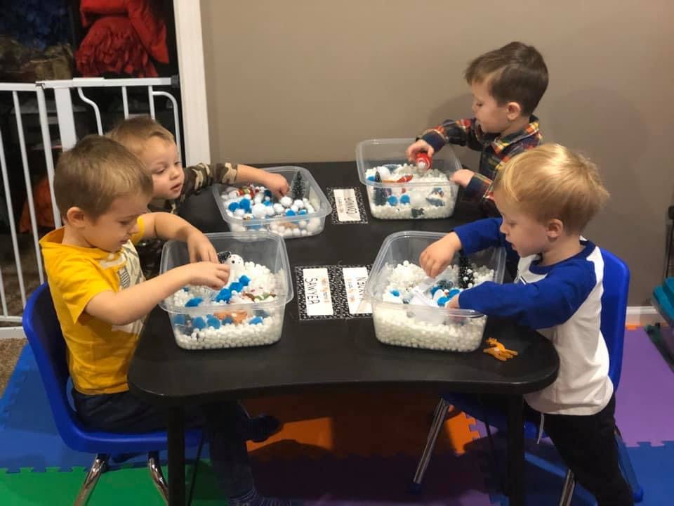 Four children playing with sensory bins at a table