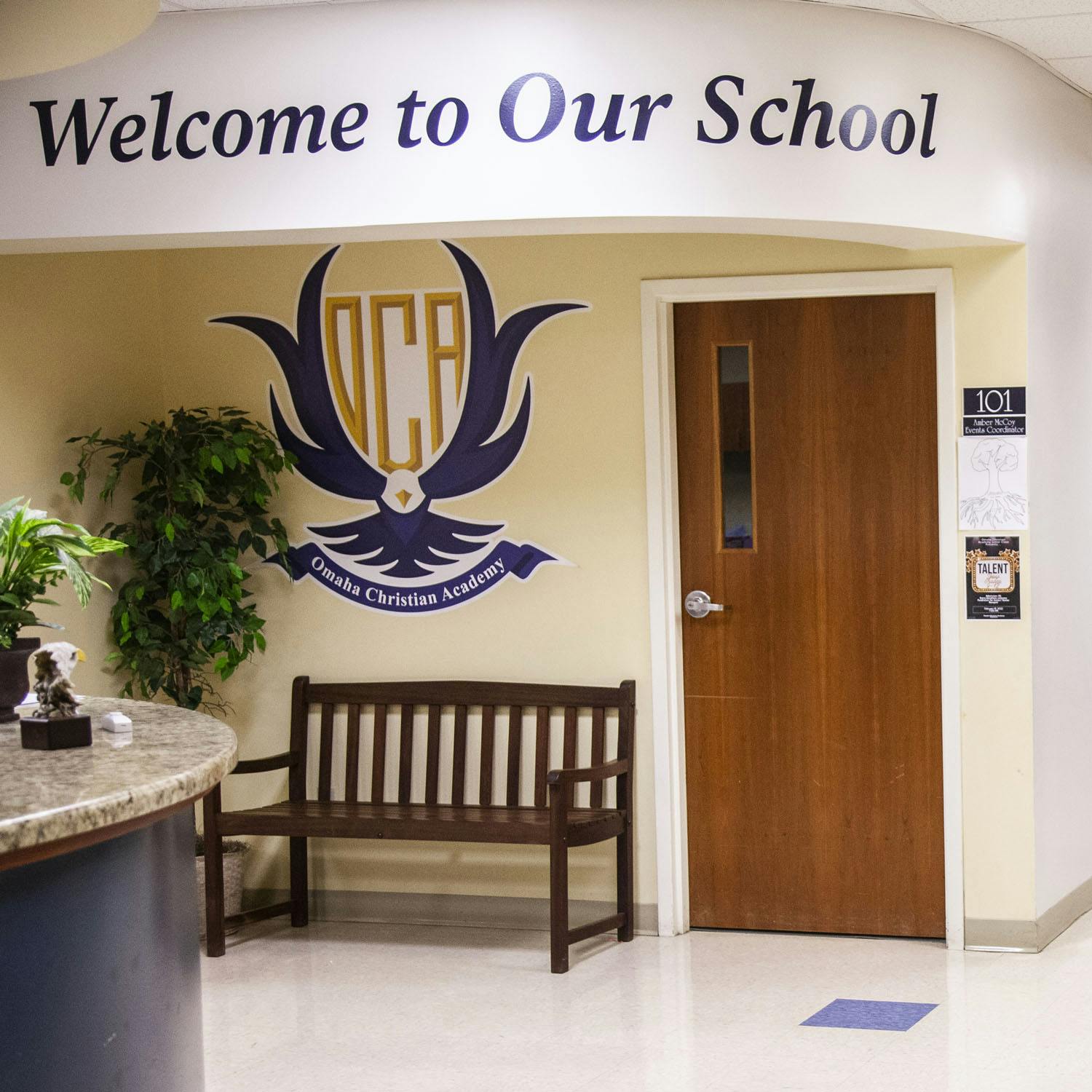 School entrance with "Welcome to Our School" sign and school logo