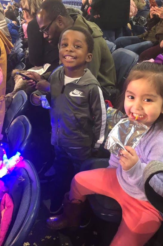 Two children sitting, one holding a snack pouch