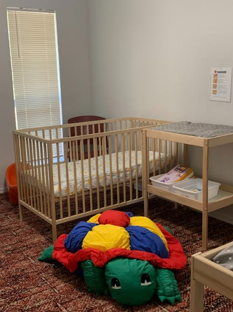 Crib and changing table with a large turtle toy on the floor