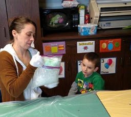 Adult and child looking at a container in a classroom