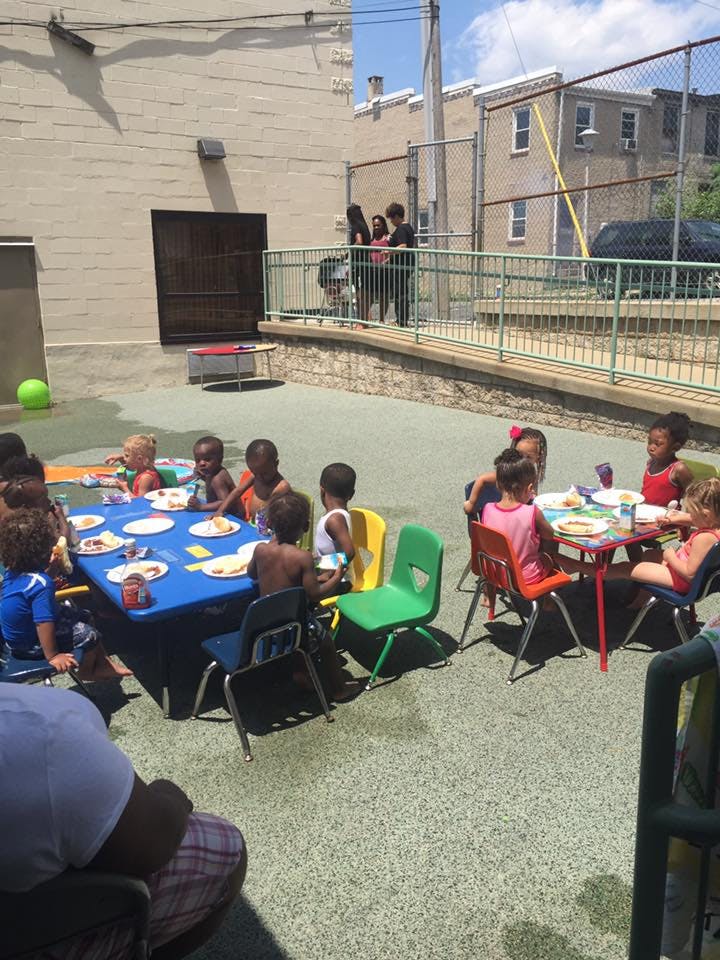 Children sitting at tables outdoors