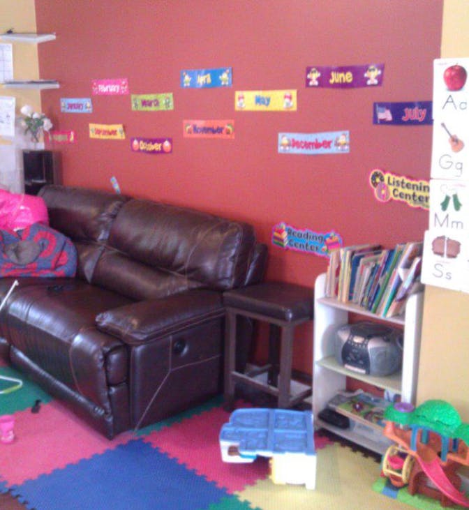 Living room with brown leather sofa, colorful floor mats, and educational posters