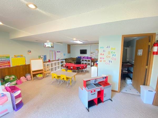 Playroom with small tables and chairs, toy kitchen, and shelves