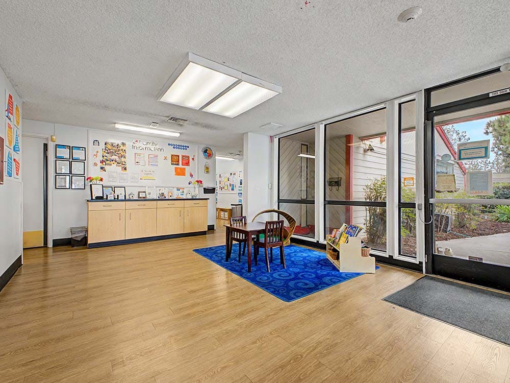 Lobby area with a small table, chairs, and family information bulletin board
