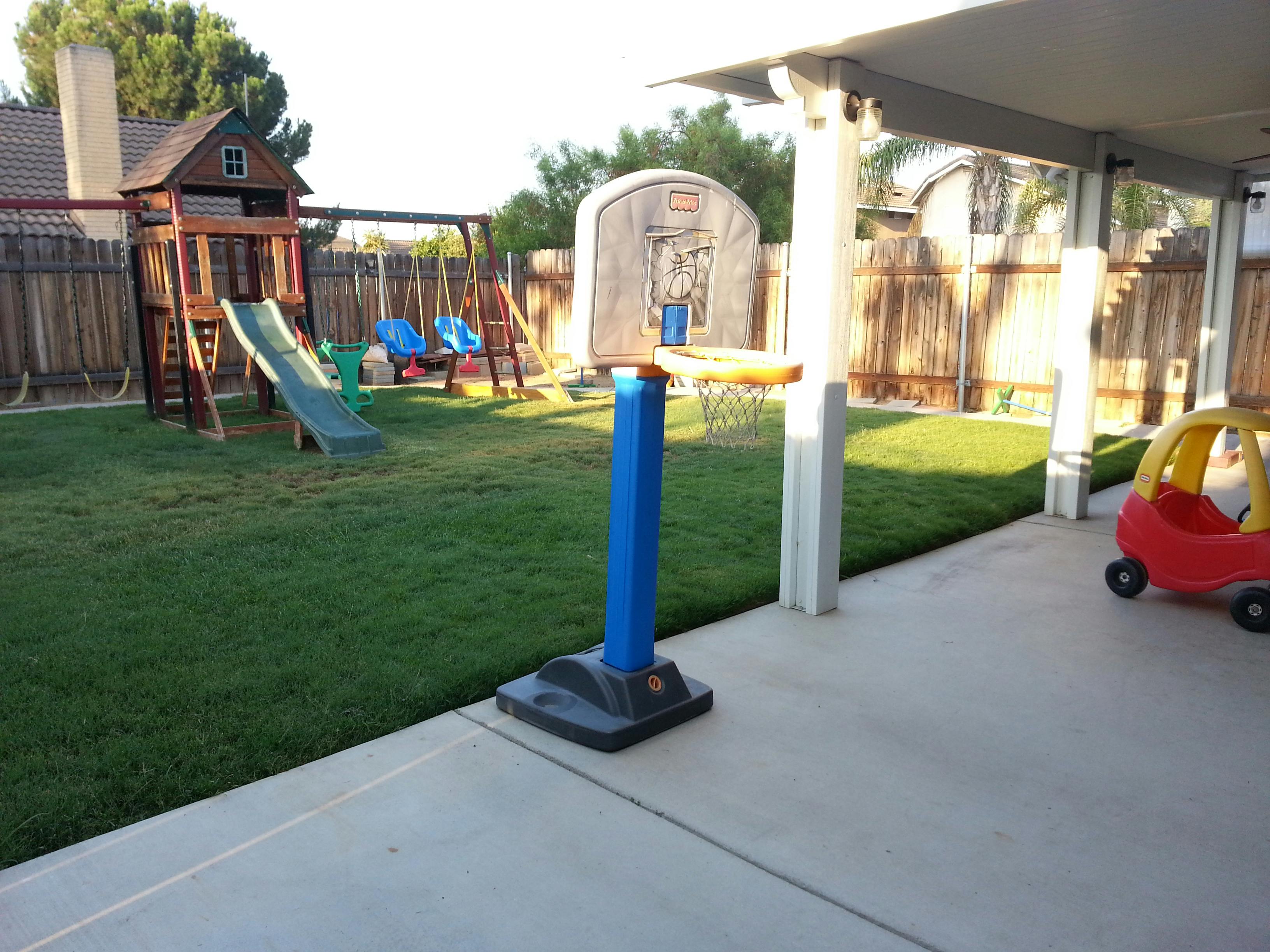 Backyard with a playset, swings, and a basketball hoop