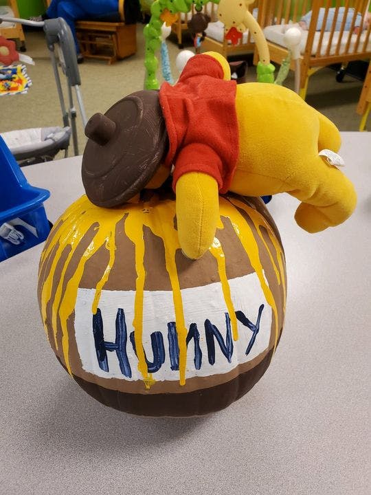 Stuffed animal on a honey pot with "HUNNY" written on it