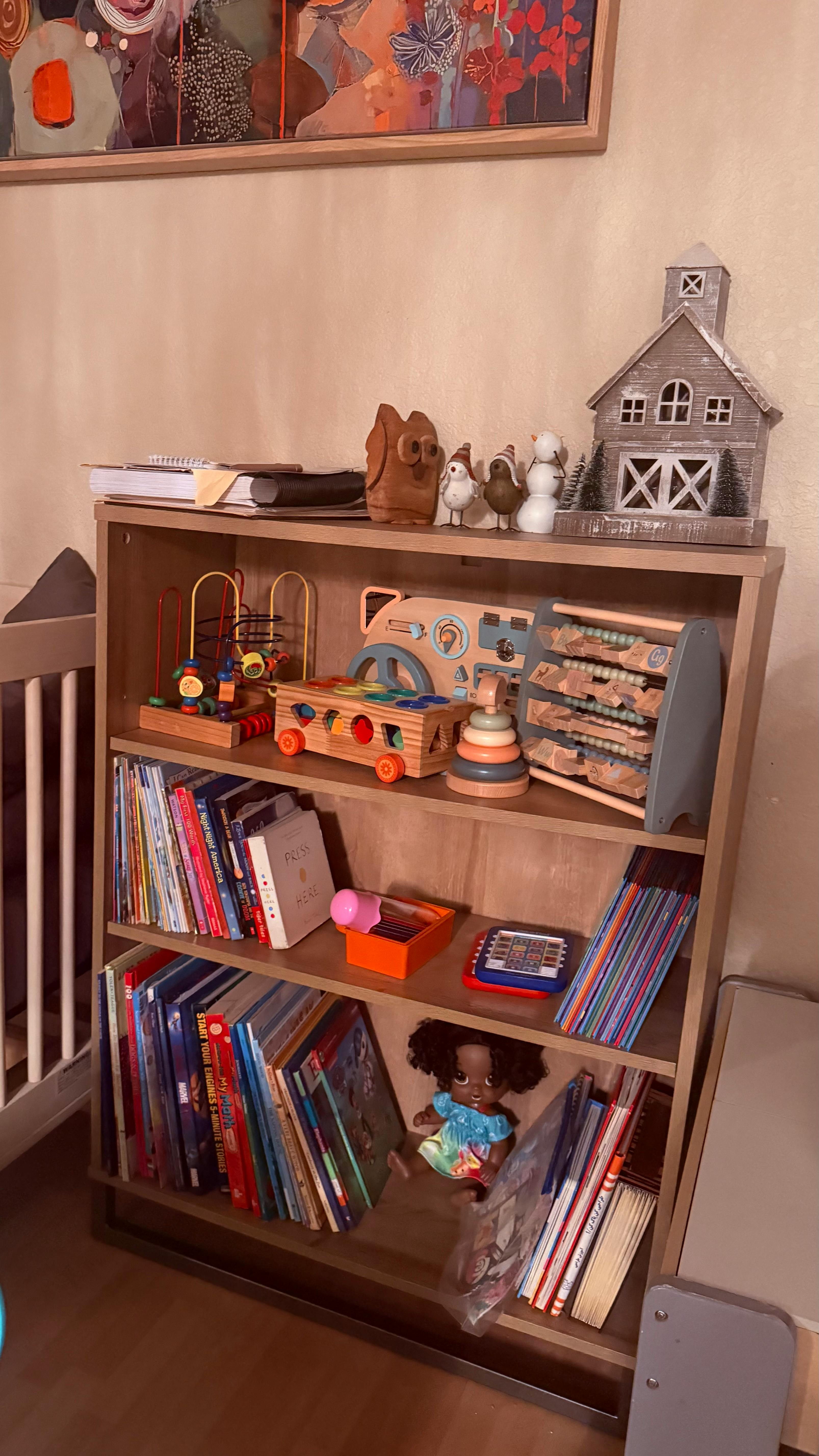Bookshelf with children's books and wooden toys, doll
