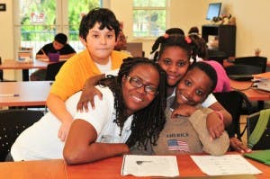 Adult and three children posing together in a classroom