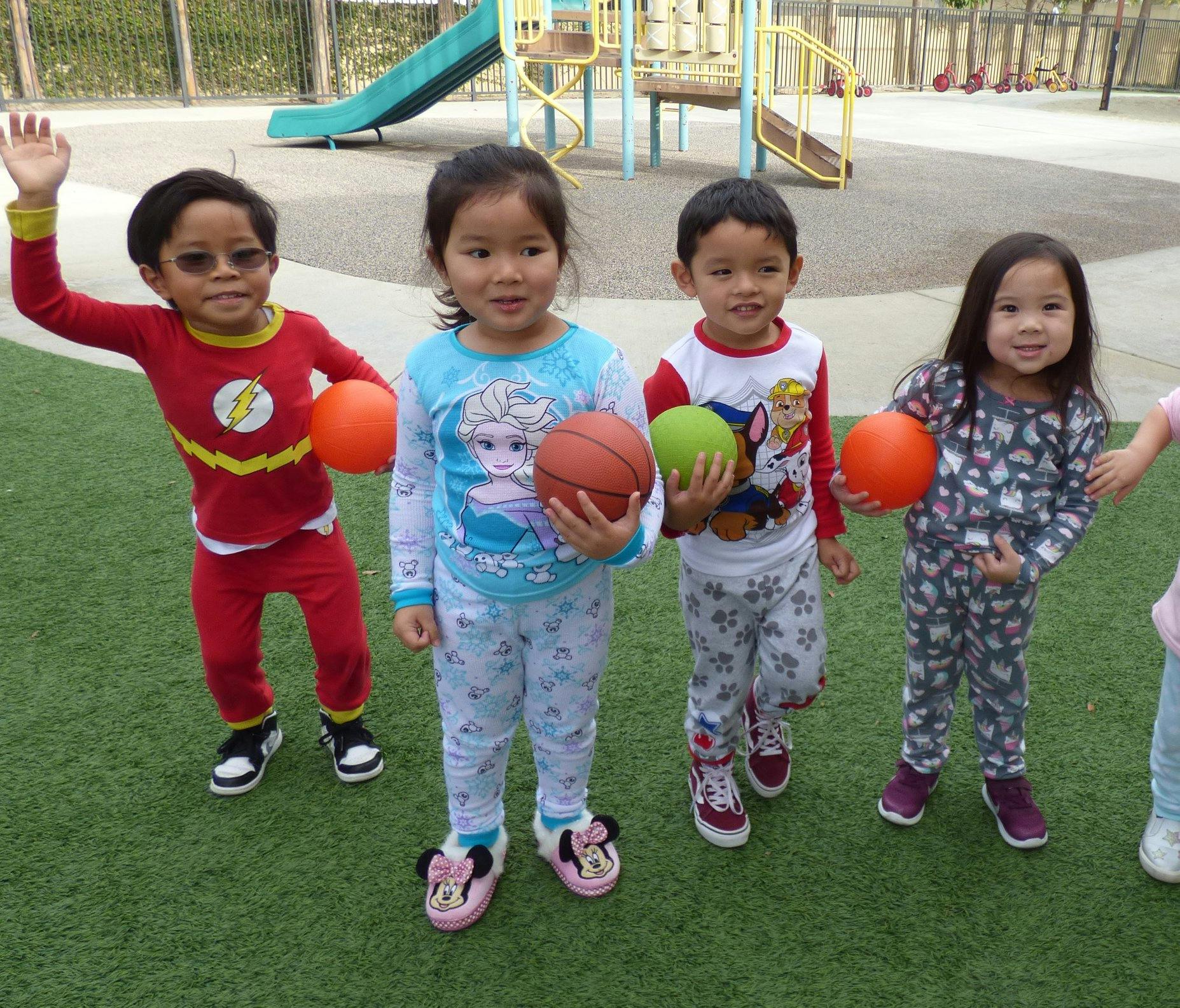 Four children holding balls on a playground