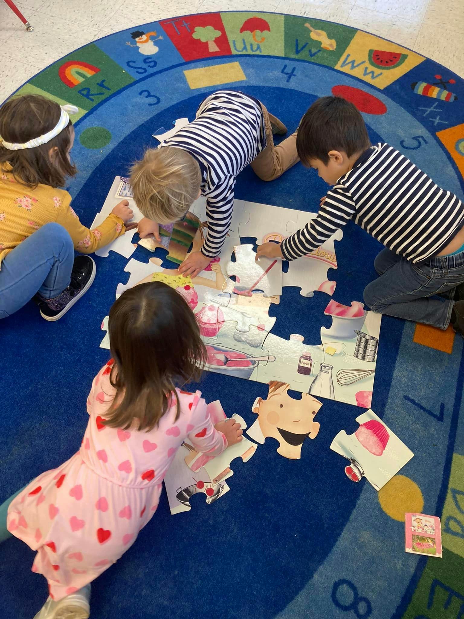 Four children on a rug assembling a large floor puzzle