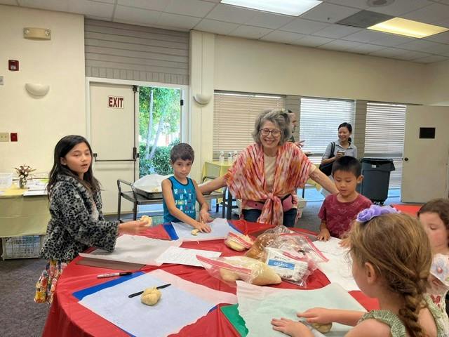 Group of children and an adult working with dough on a table