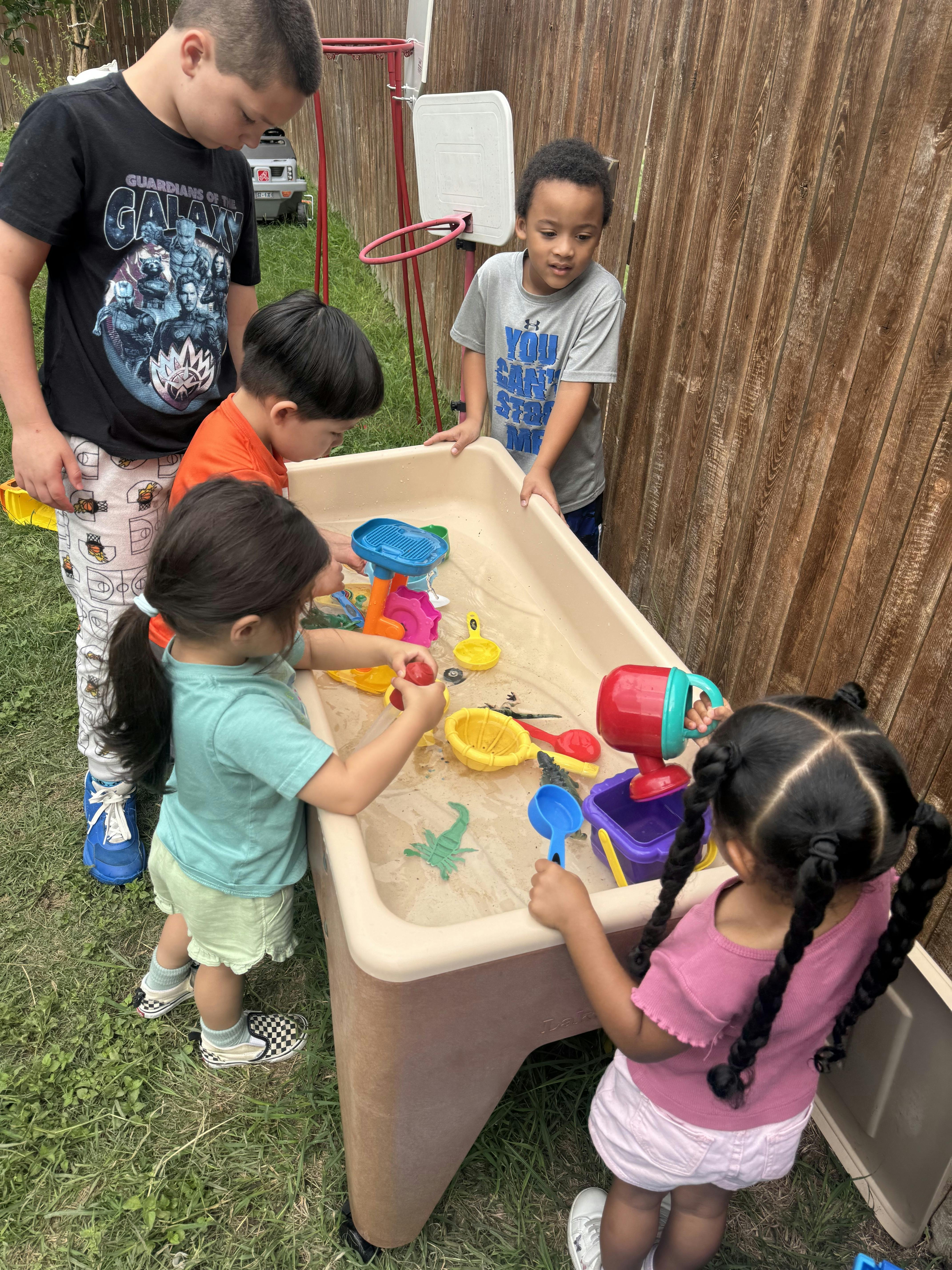 Group of children playing with toys in a water table outdoors