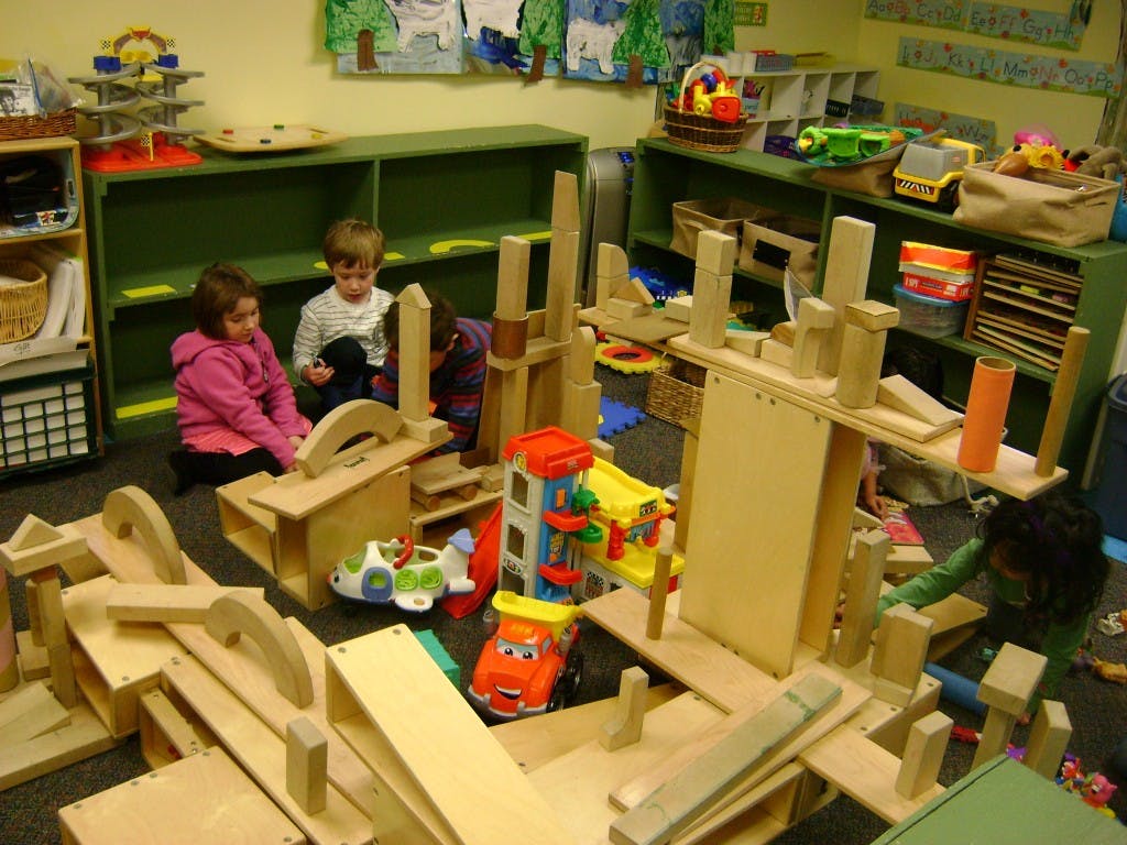 Two children playing with wooden blocks and toys in a classroom
