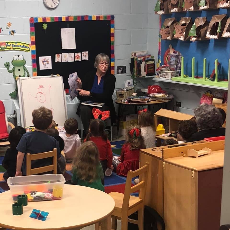 Adult person reading to children in a classroom