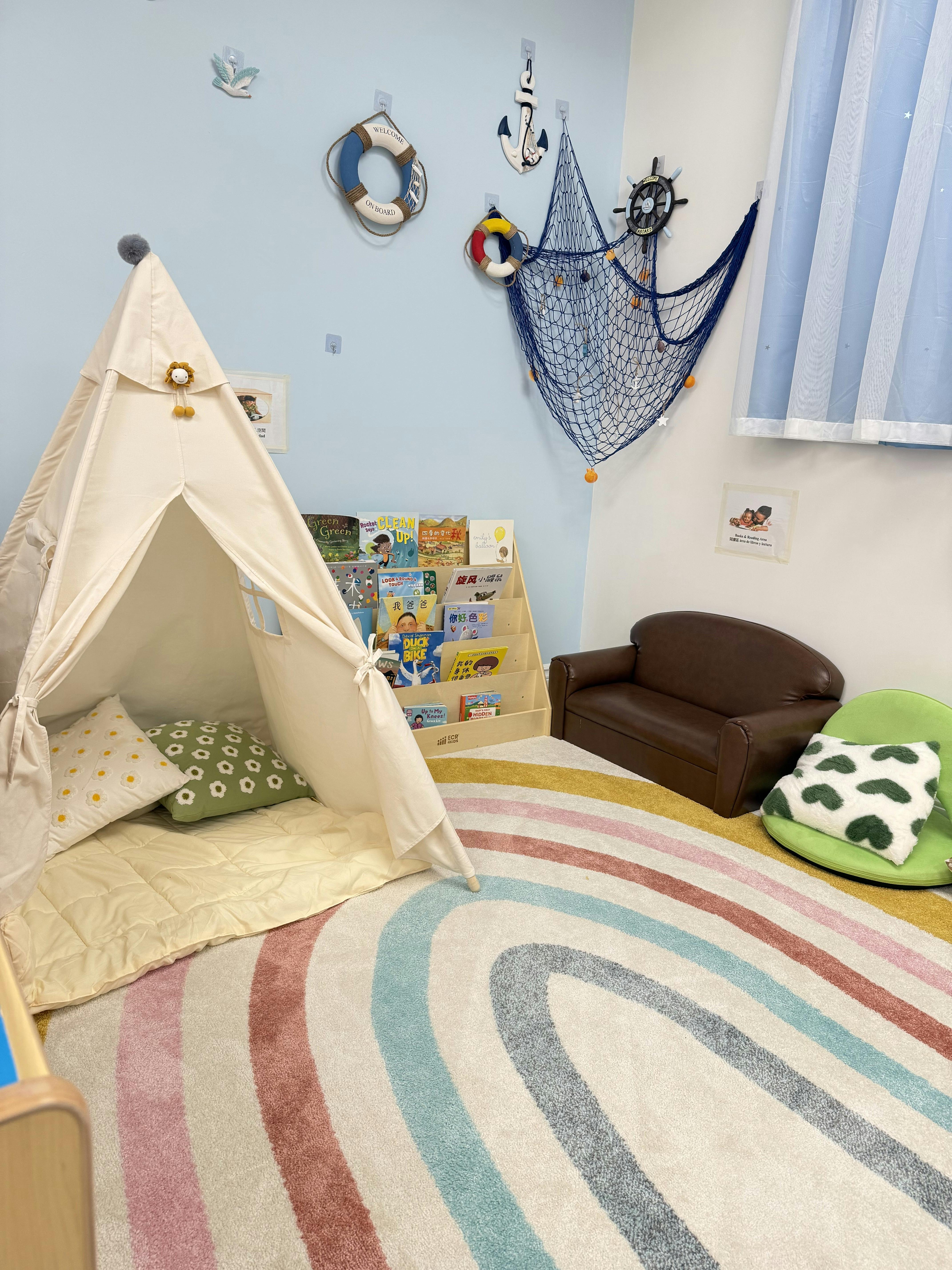 Playroom with a teepee, book display, and rainbow rug