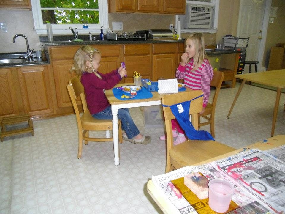 Two children sitting at a table in a kitchen