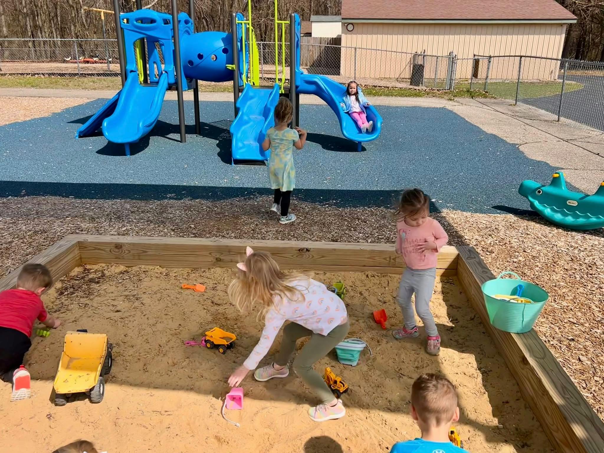Children playing in a sandbox and on a playground slide