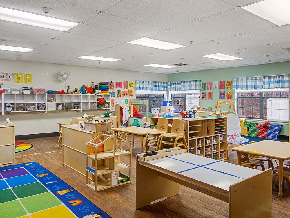 Empty colorful classroom with small tables, chairs, and learning materials