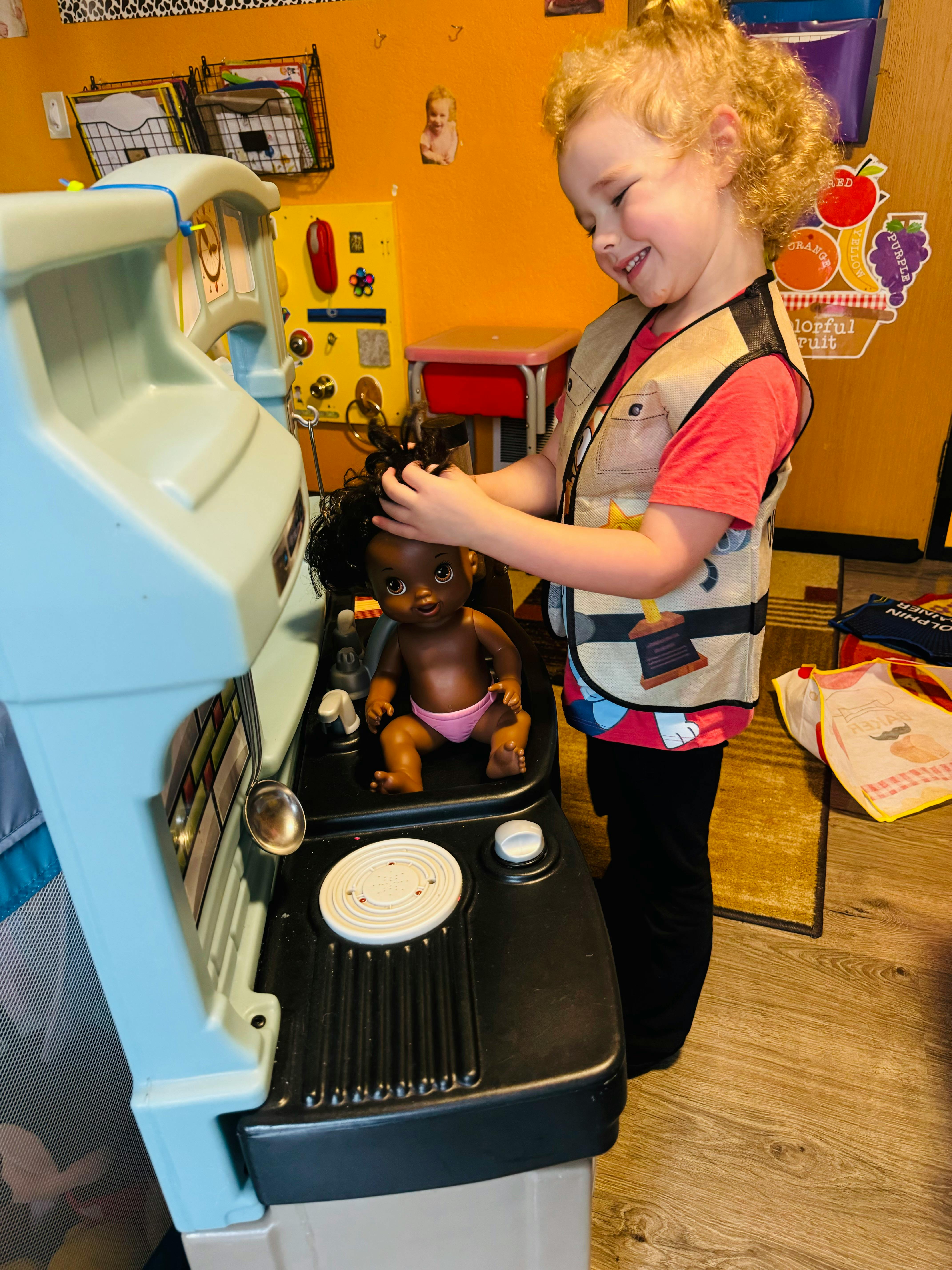 Child playing with a doll at a toy kitchen