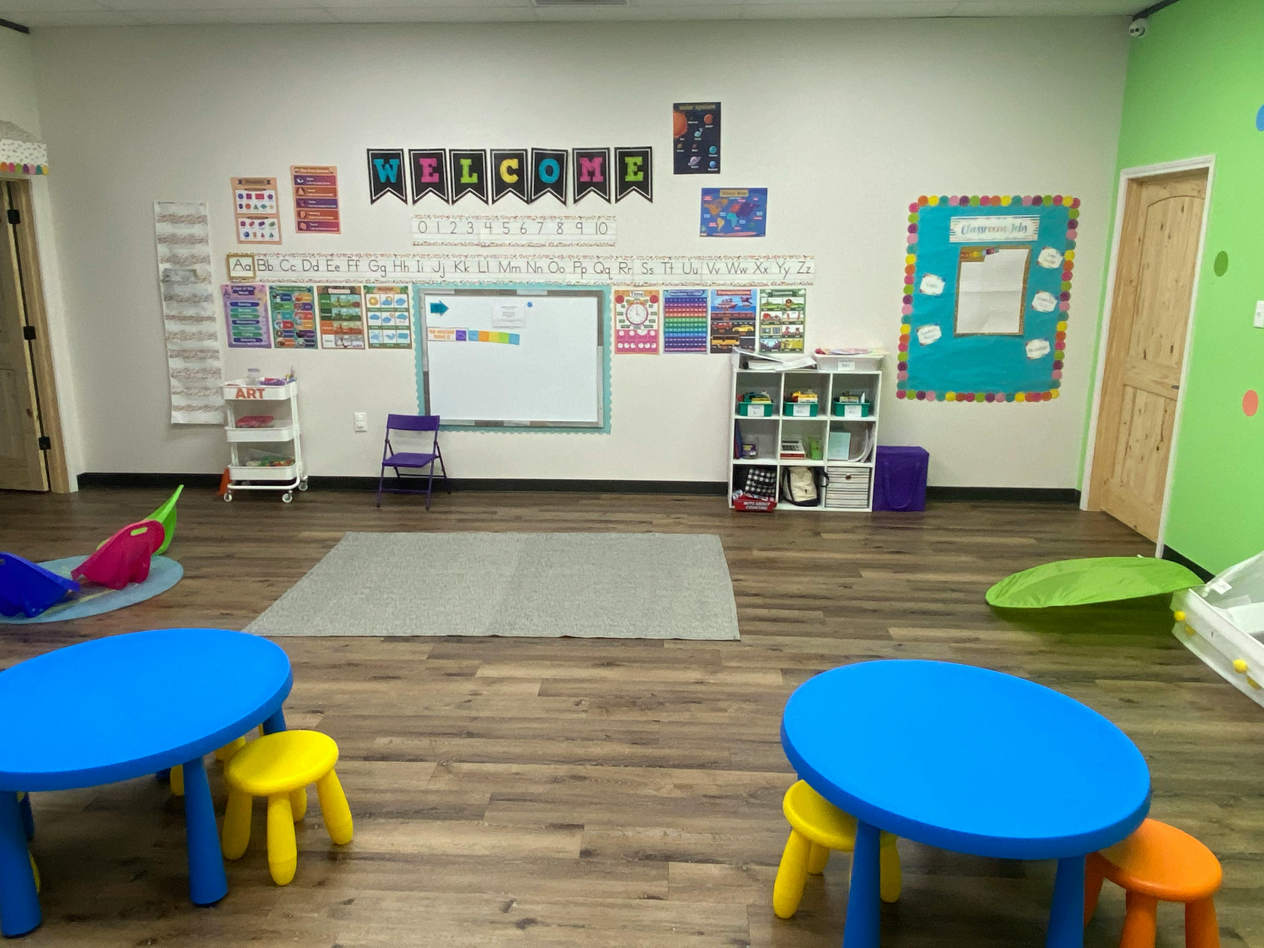 Empty classroom with small blue tables and yellow stools