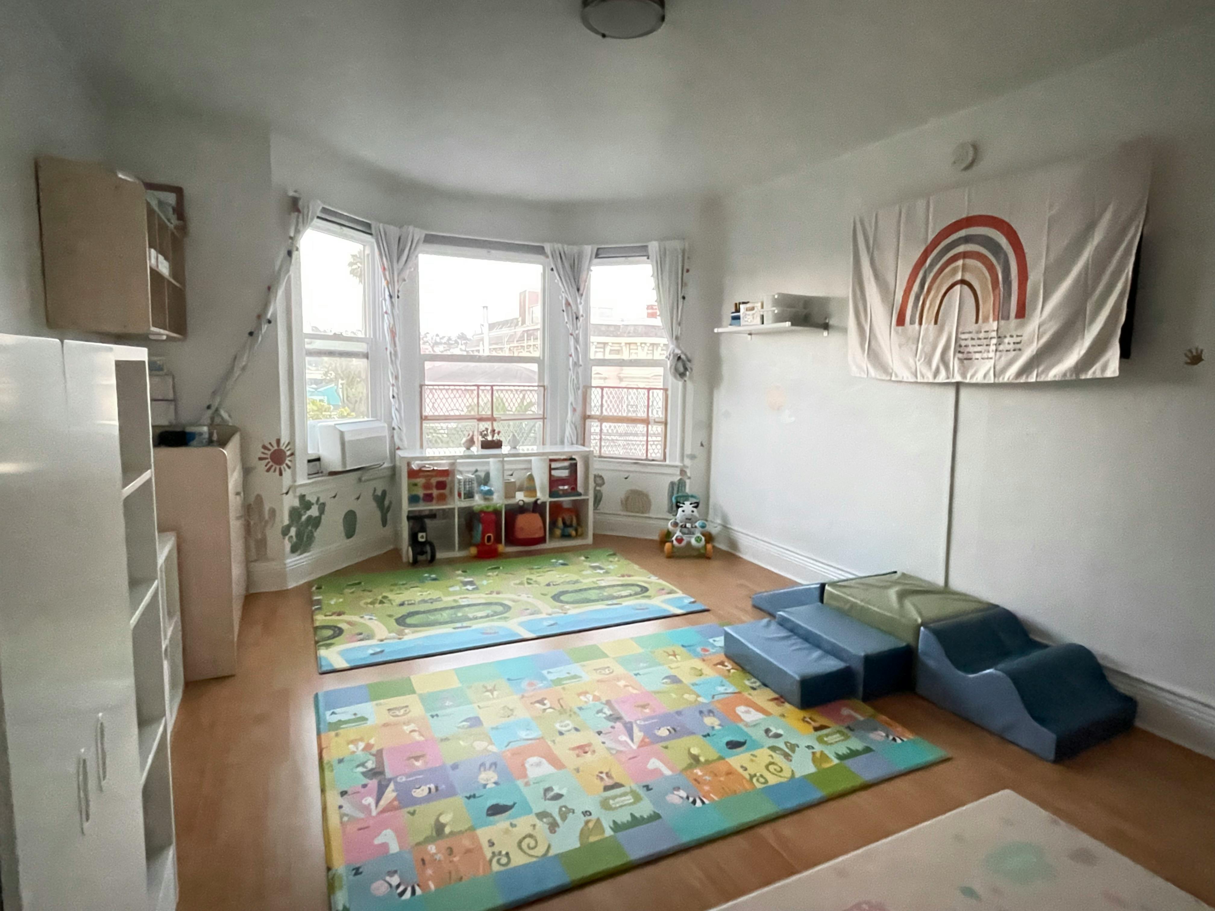 Playroom with colorful mats, shelves, and a rainbow tapestry