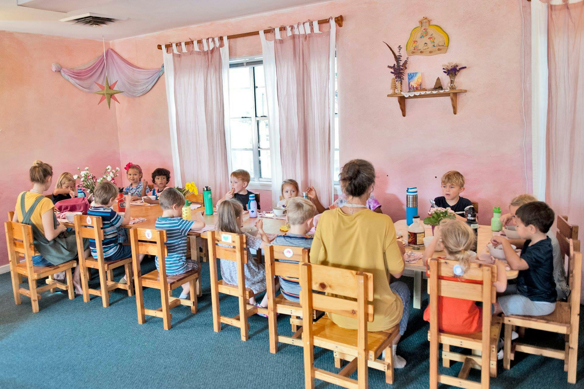 Adults and children sitting at tables in a classroom