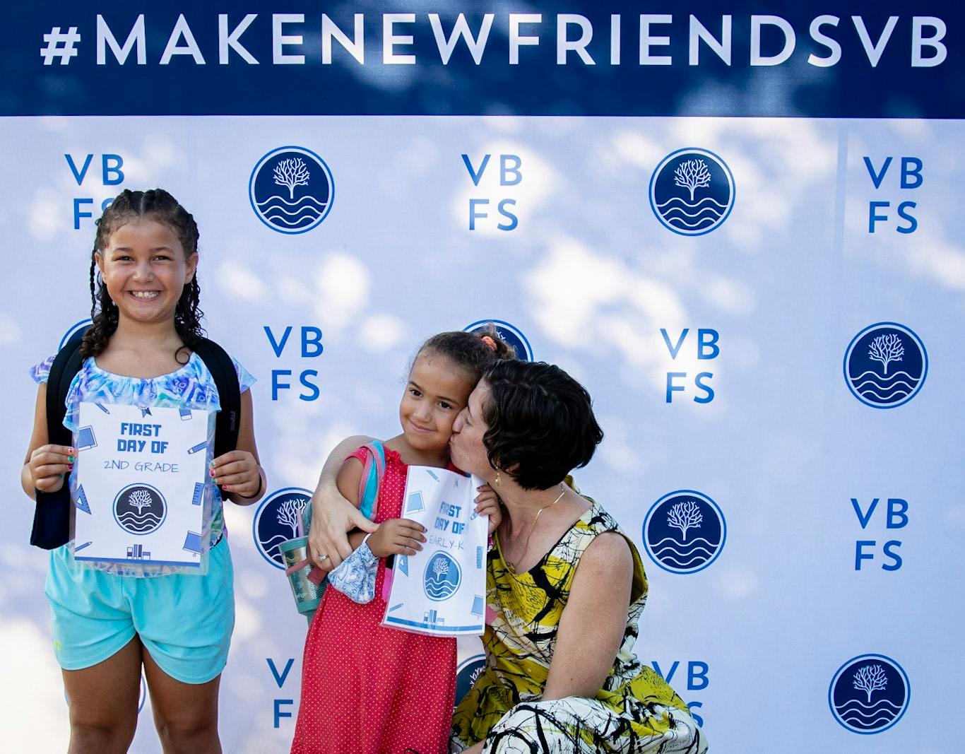 Two children and an adult holding papers in front of a backdrop