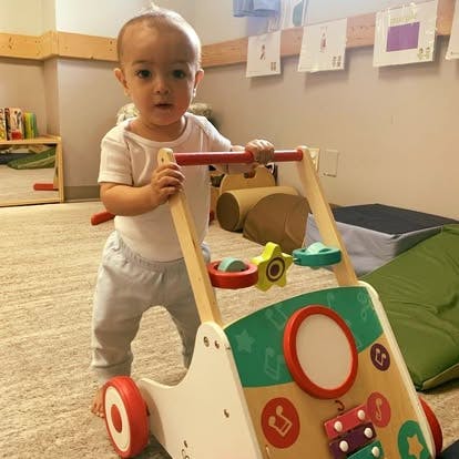 Child standing and holding onto a wooden activity walker