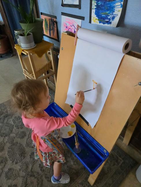 Child painting on paper attached to an easel