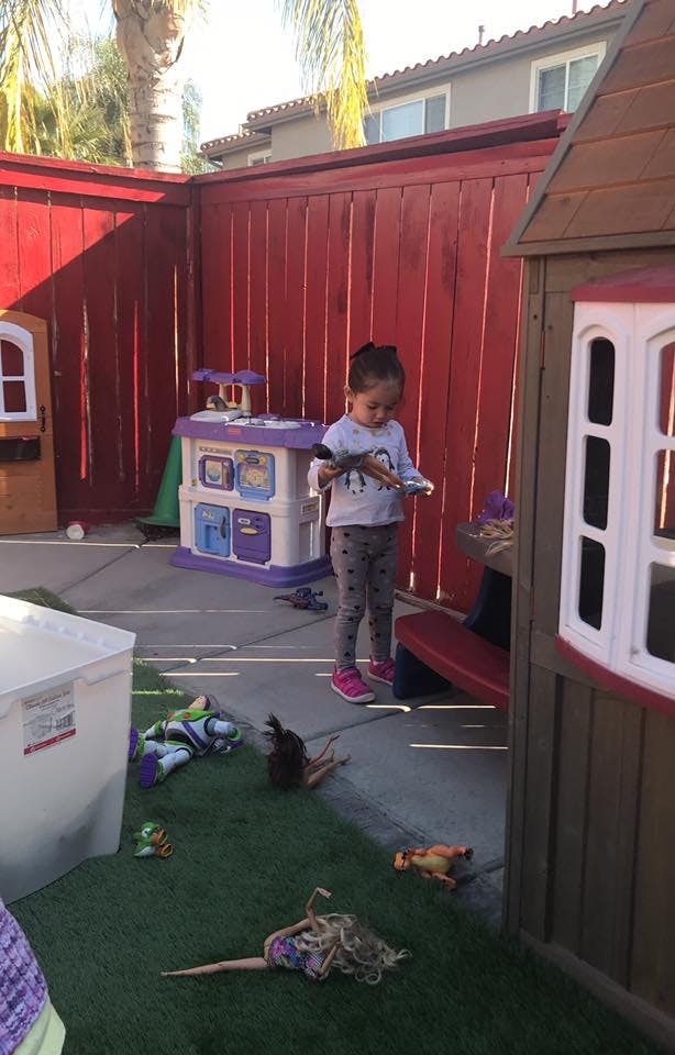 Child standing in a play area holding a toy