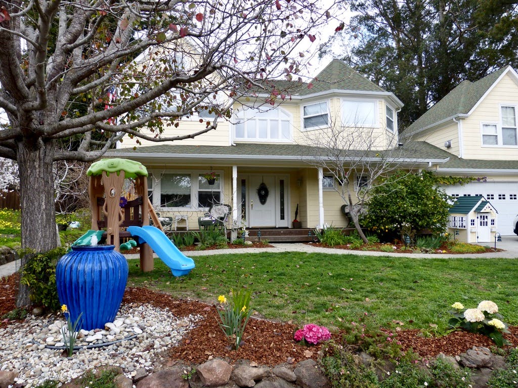 Front yard with a play structure and a large house in-ground house