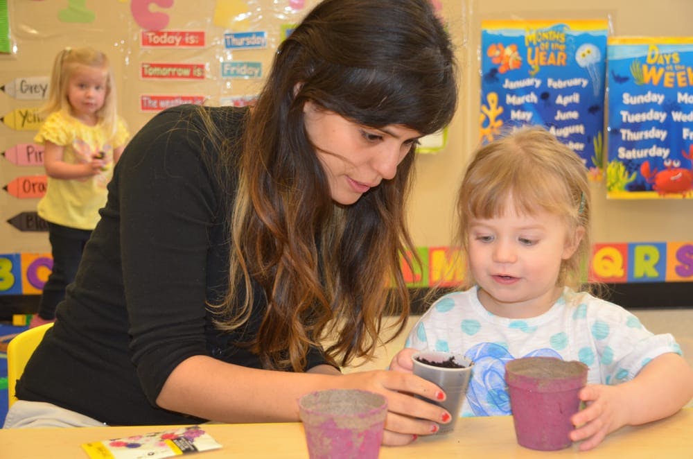 Person and child looking at small potted plants