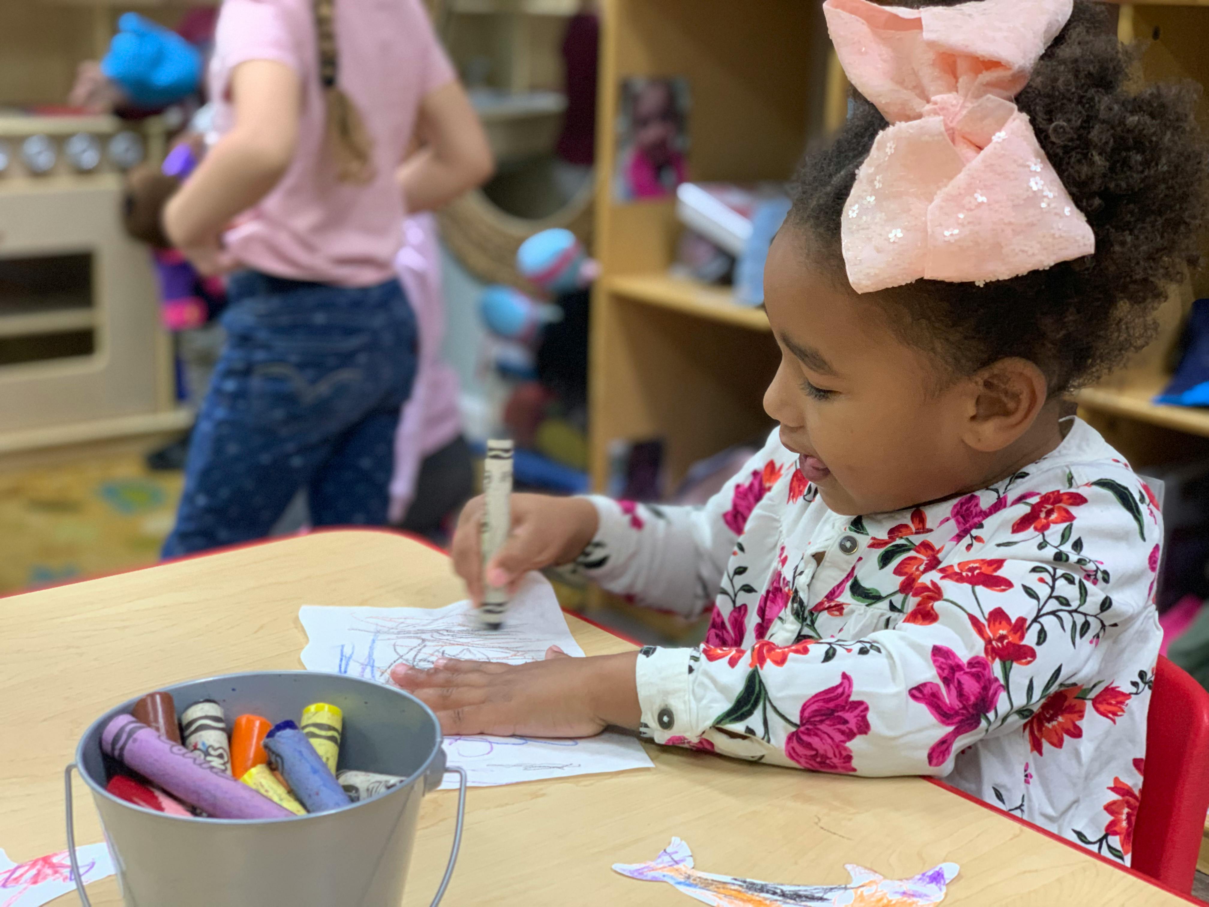 Child drawing with a crayon at a table