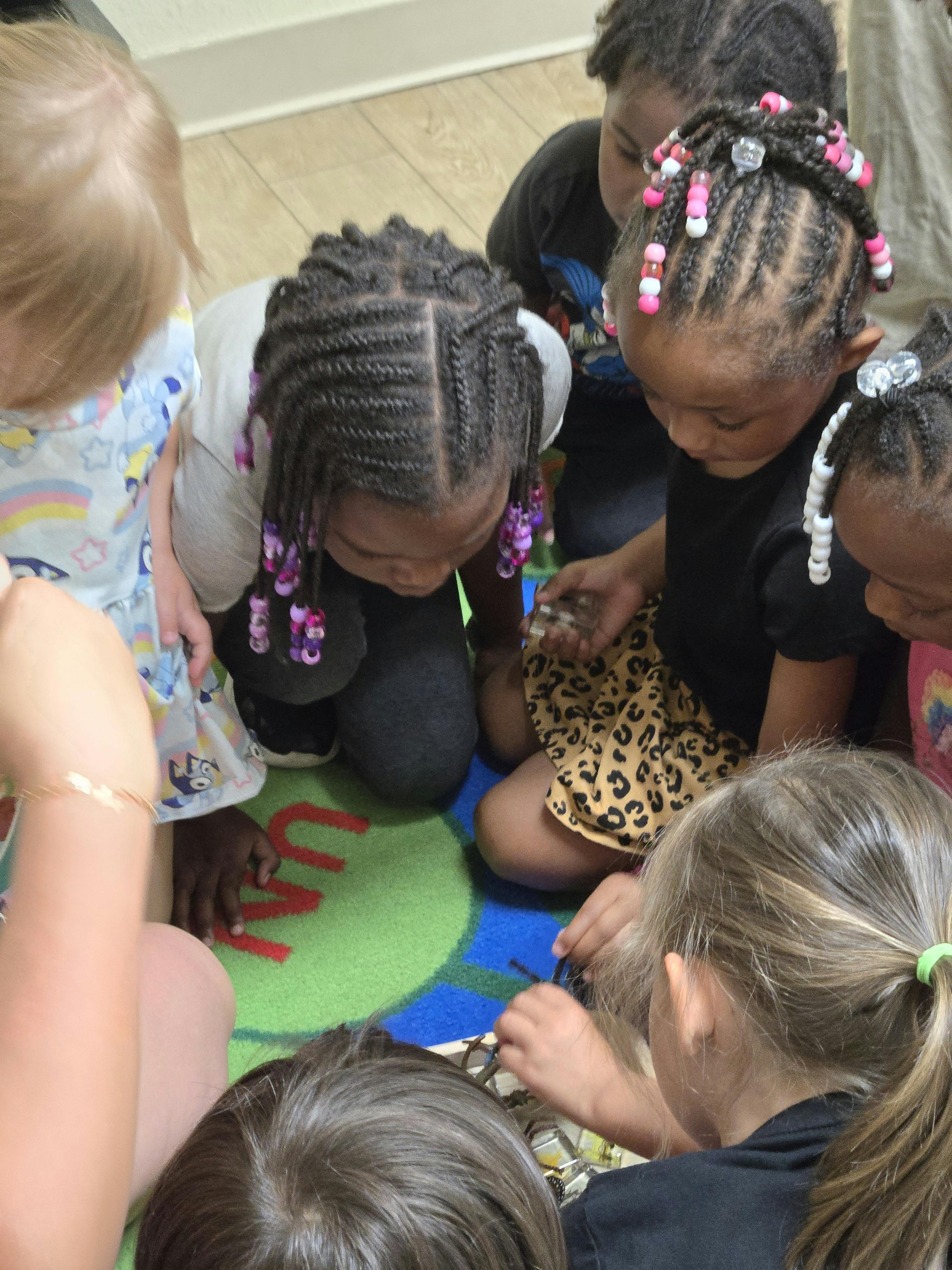 Children gathered around an object on the floor