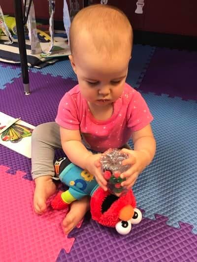 Child sitting on a mat, holding a toy