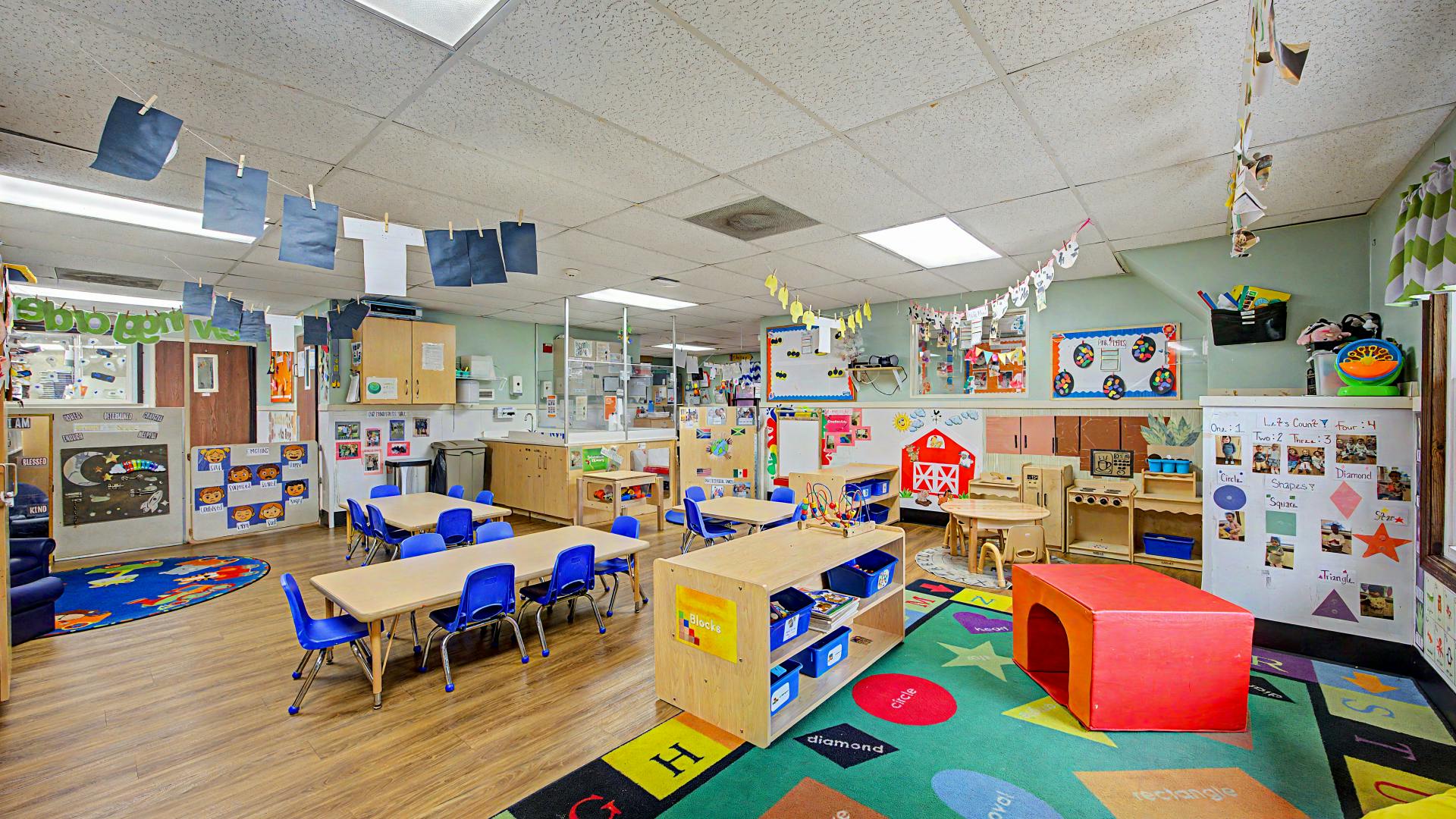 Empty colorful preschool classroom with small tables and chairs