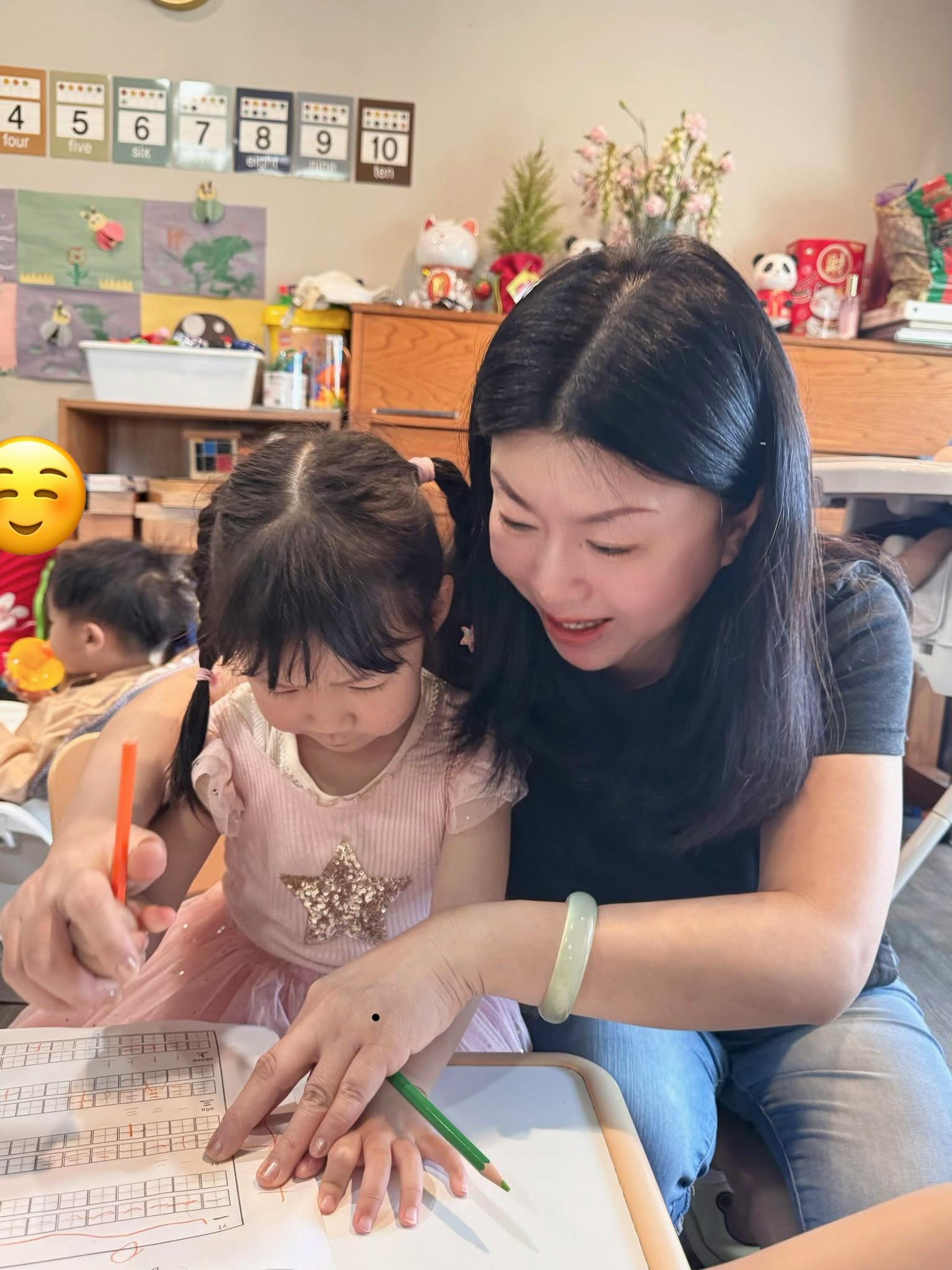 Adult helping a child write with a pencil