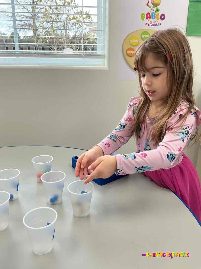 Child looking down at white cups on a table