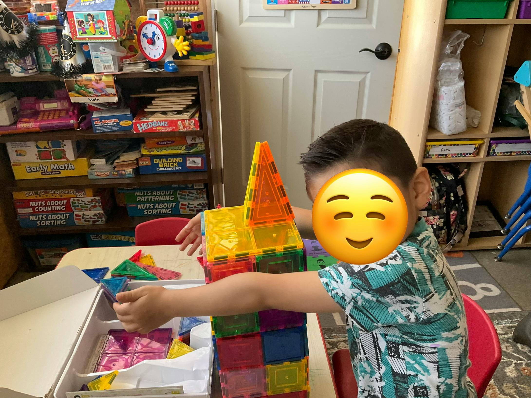 Child building a structure with colorful magnetic tiles at a table