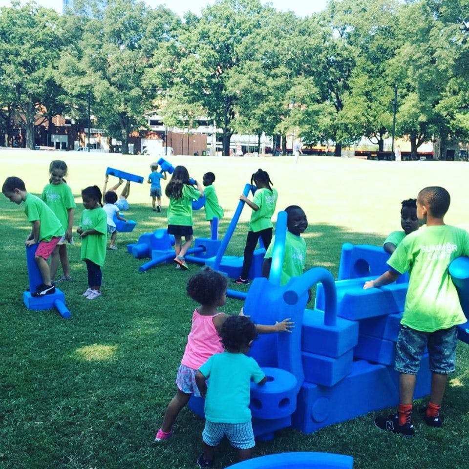 Children playing with blue building blocks outdoors