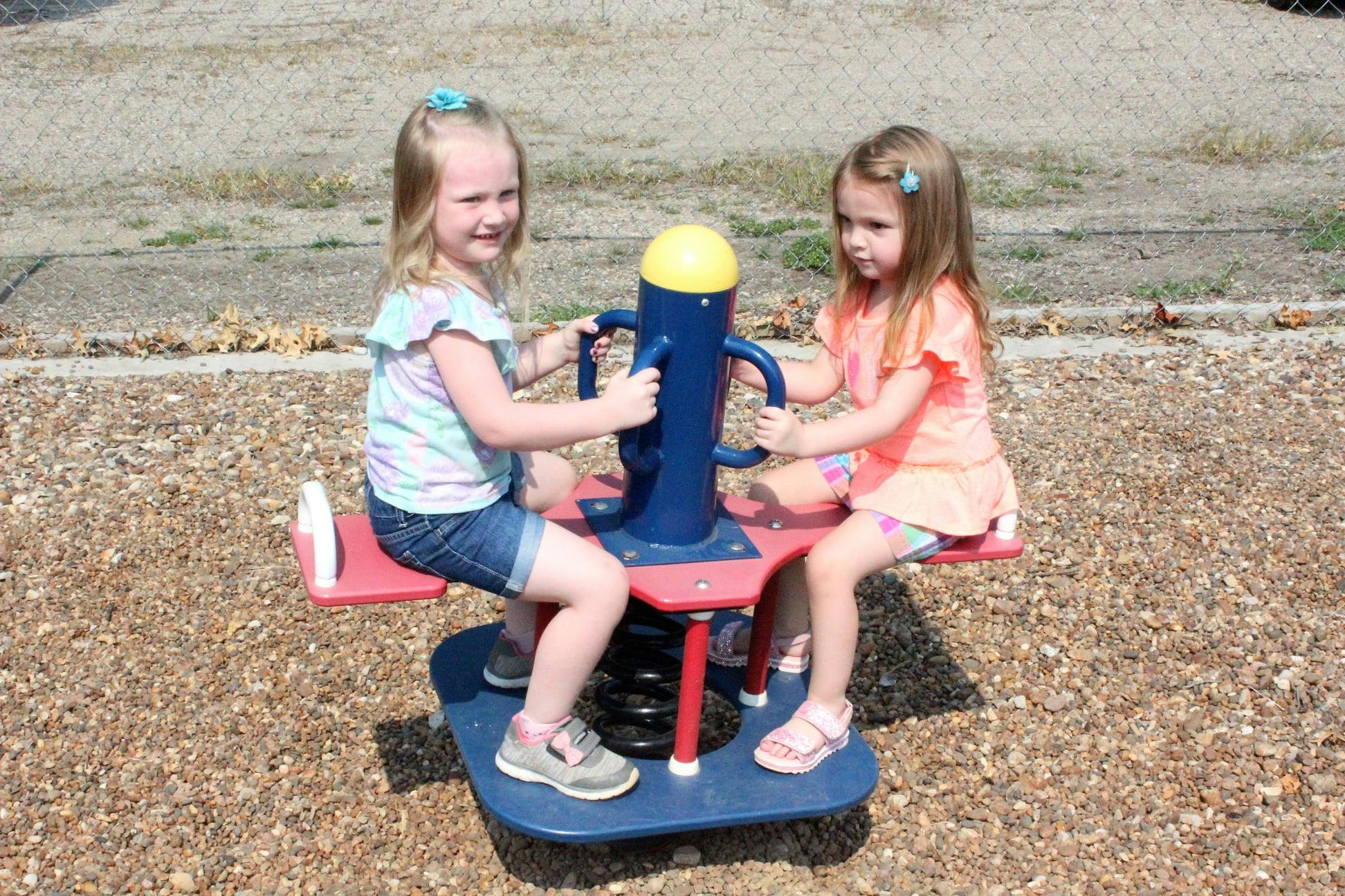 Two children on a playground seesaw