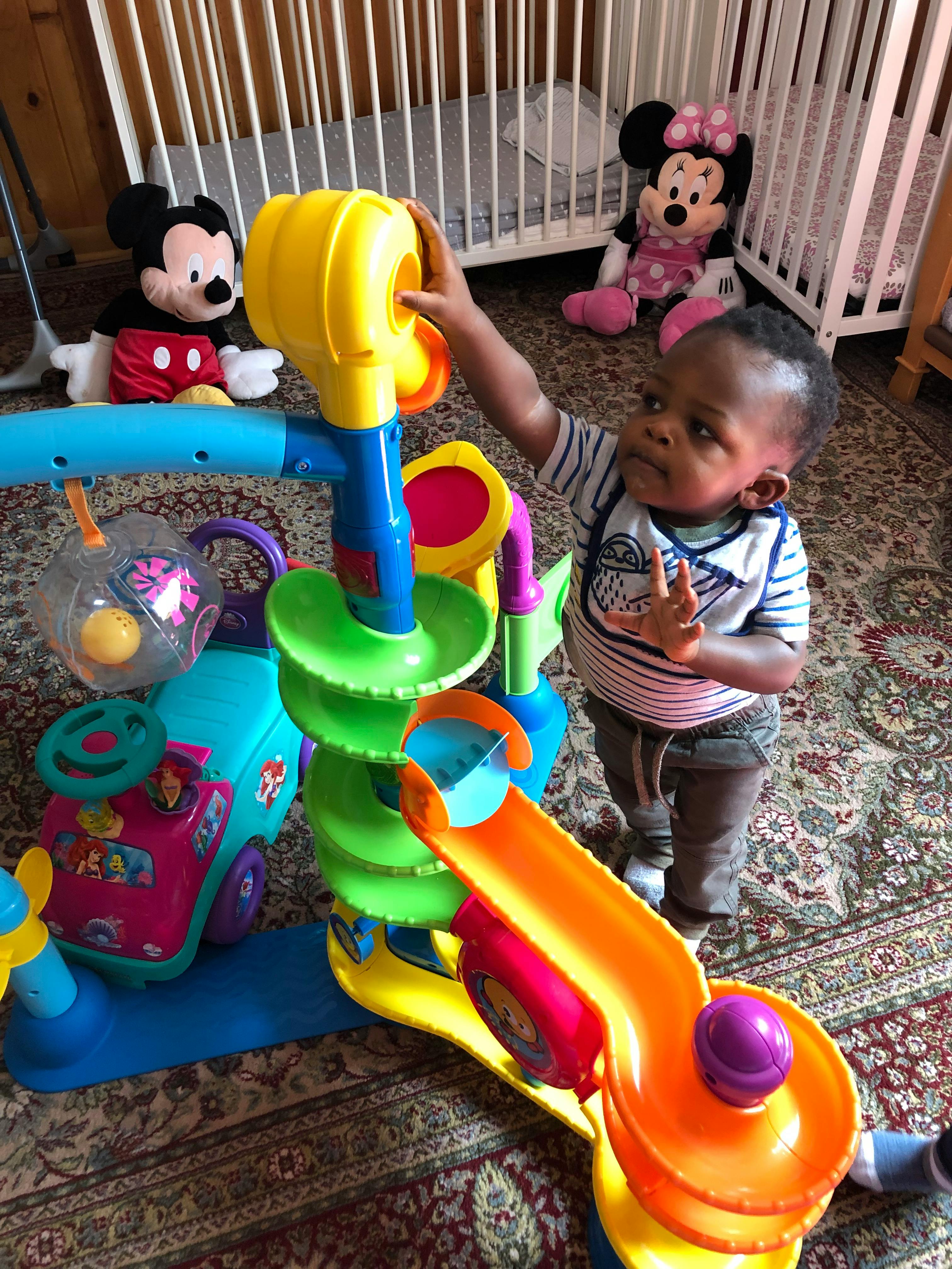 Child playing with a colorful toy ball run