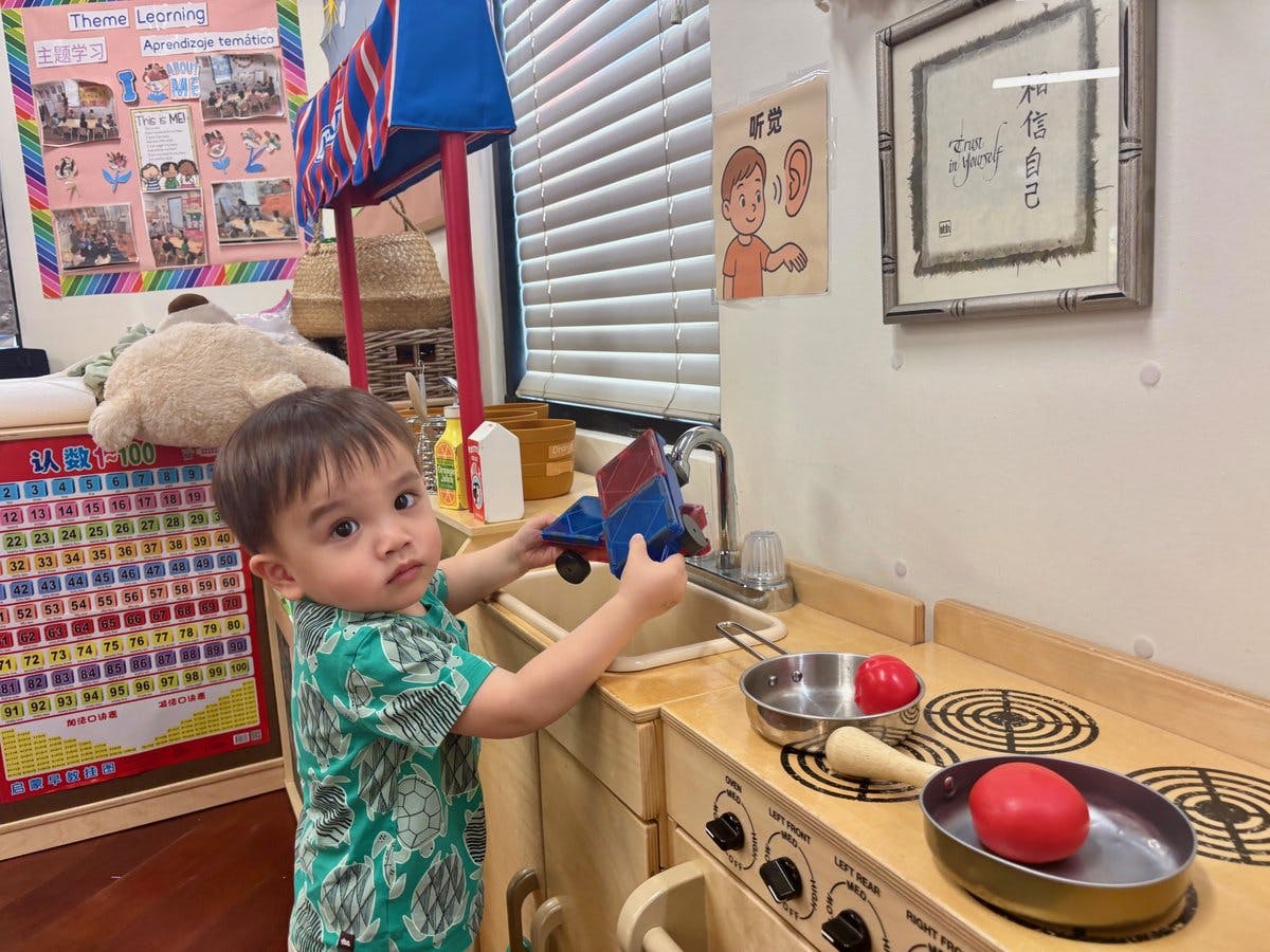 Child playing with a toy truck at a play kitchen
