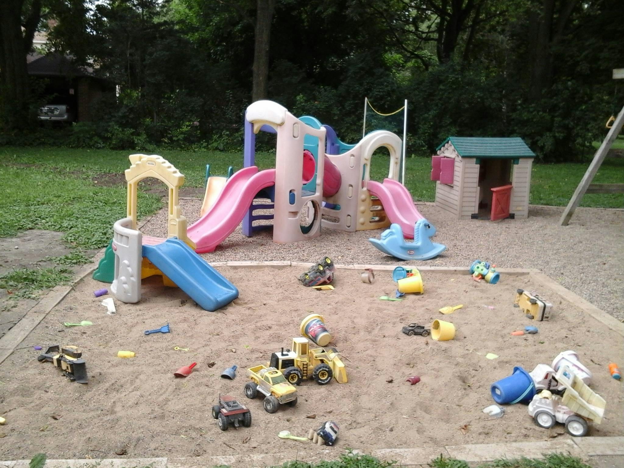 Playground with slides, playhouse, and sandbox with toys